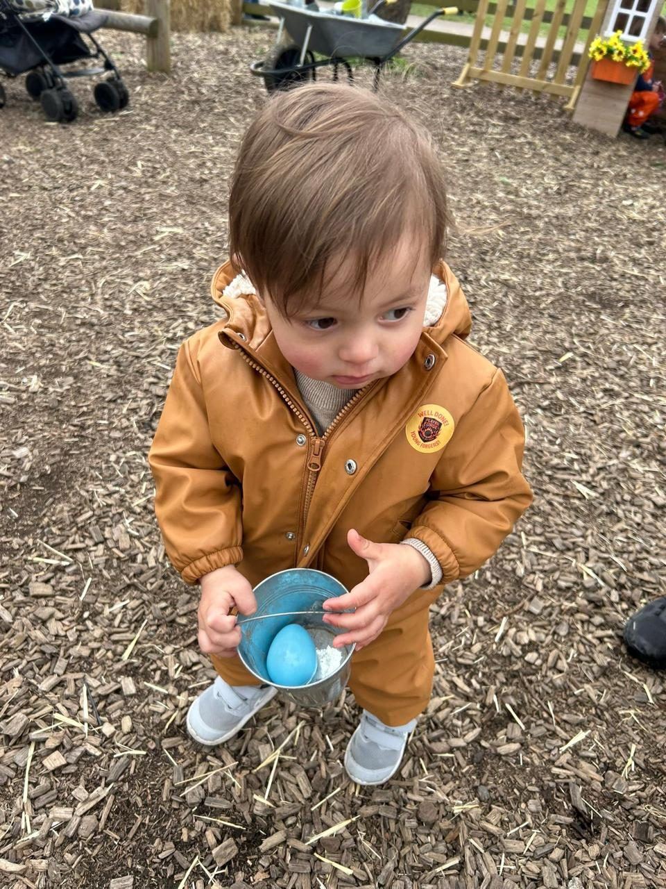 Infant with a bucket in outdoor play at ME Montessori Nursery Aylesbury