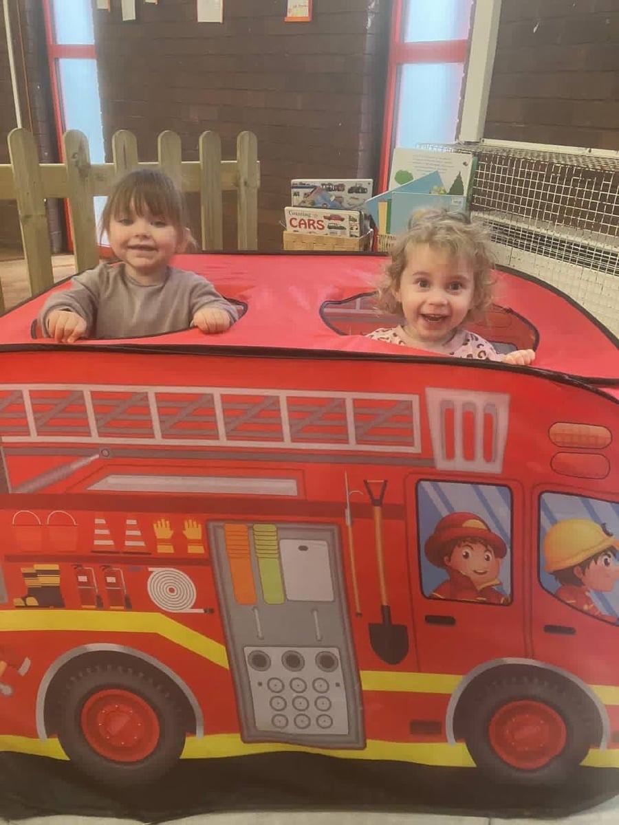 Infants playing in a fire engine tent at ME Montessori Nursery Aylesbury — imaginative play